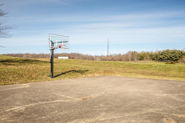 view of sport court featuring a lawn and a rural view