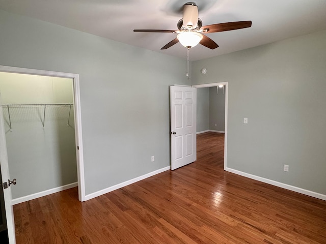 unfurnished bedroom featuring a walk in closet, ceiling fan, a closet, and hardwood / wood-style flooring