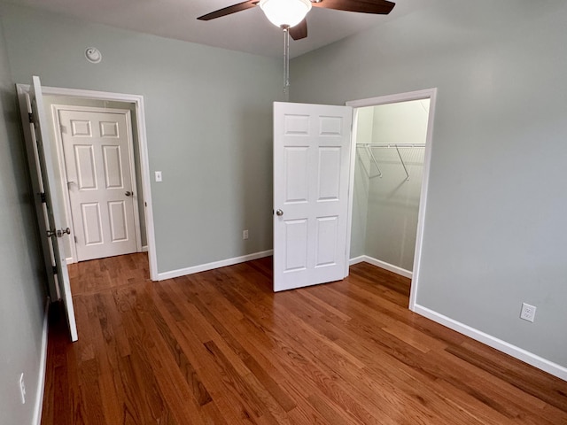 unfurnished bedroom with wood-type flooring, a closet, a spacious closet, and ceiling fan