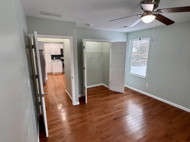 unfurnished bedroom featuring wood-type flooring, a closet, and ceiling fan