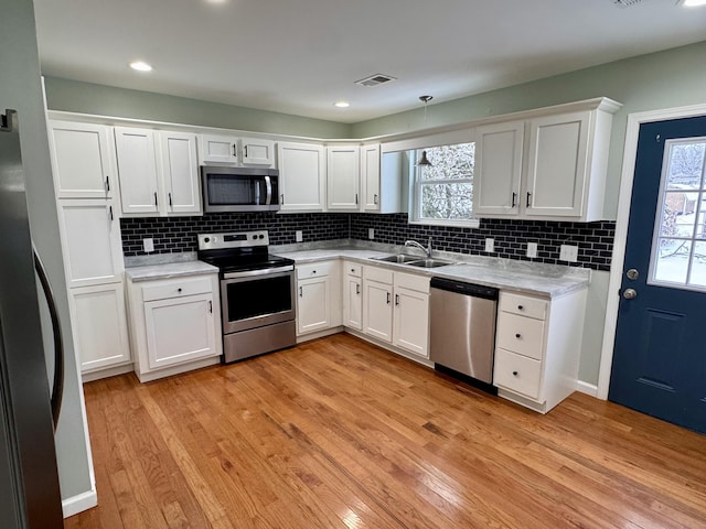 kitchen featuring sink, light stone countertops, light hardwood / wood-style floors, white cabinetry, and stainless steel appliances