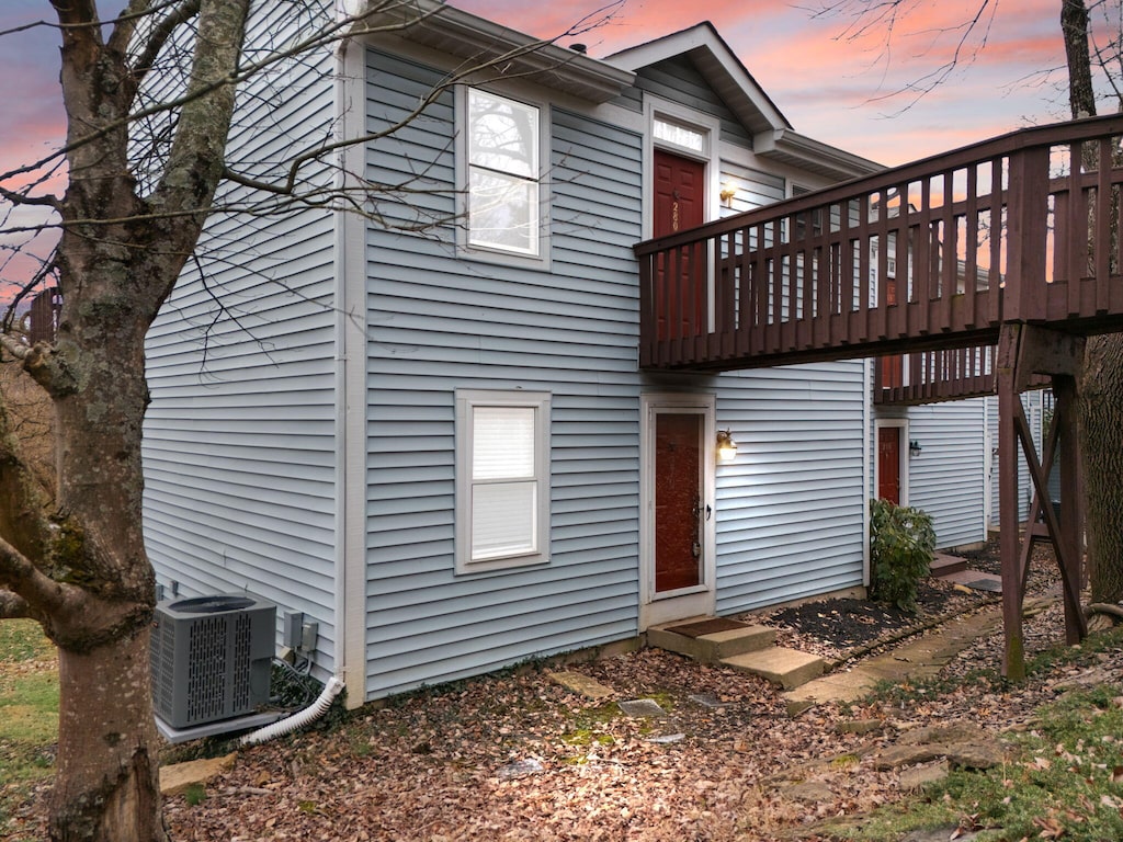 back house at dusk featuring central AC unit and a deck