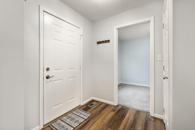 doorway to outside with dark wood-type flooring and a textured ceiling