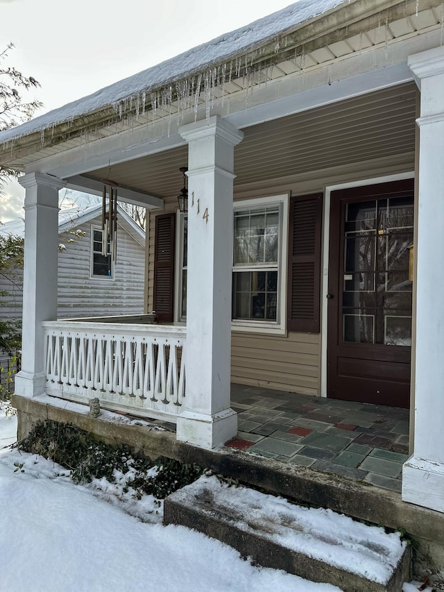 snow covered property entrance with covered porch