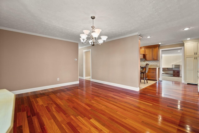 interior space with hardwood / wood-style flooring, a textured ceiling, crown molding, and a chandelier