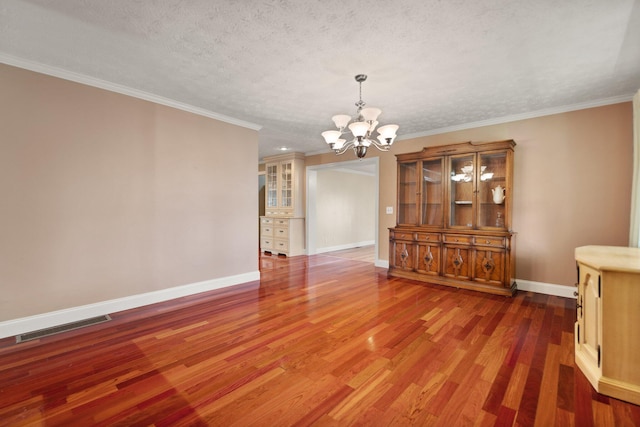 unfurnished dining area with a chandelier, a textured ceiling, dark hardwood / wood-style floors, and crown molding