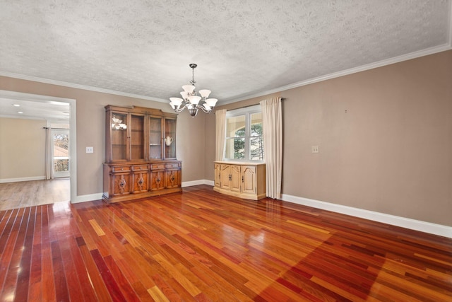 unfurnished dining area with wood-type flooring, ornamental molding, a textured ceiling, and an inviting chandelier