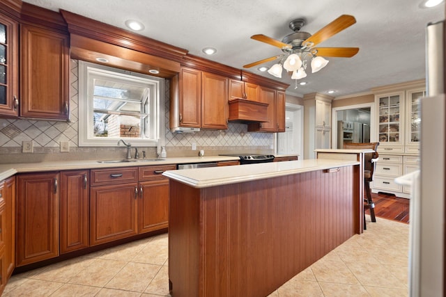 kitchen featuring backsplash, custom exhaust hood, ceiling fan, sink, and light tile patterned floors