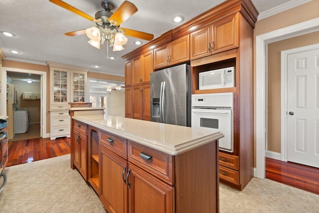 kitchen with ceiling fan, a center island, white appliances, and ornamental molding