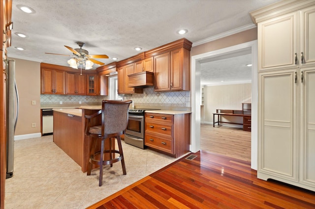 kitchen featuring a center island, crown molding, ceiling fan, custom range hood, and stainless steel appliances