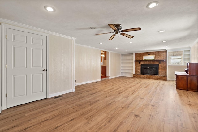 unfurnished living room with a brick fireplace, ceiling fan, crown molding, light hardwood / wood-style flooring, and built in features