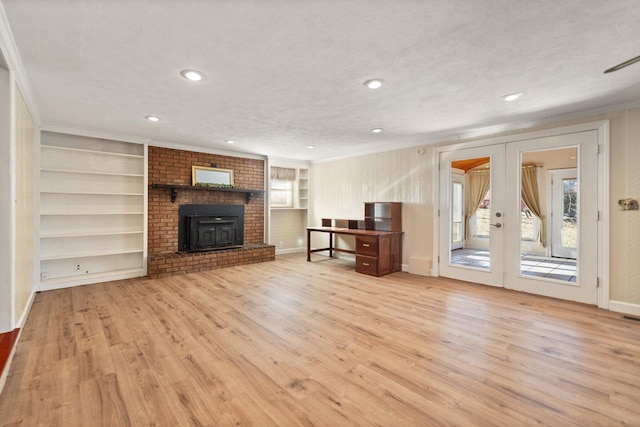 unfurnished living room with french doors, crown molding, built in features, light hardwood / wood-style floors, and a wood stove