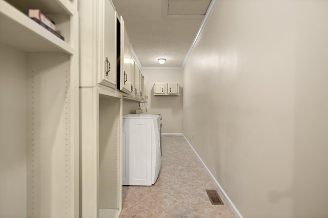 washroom with a textured ceiling, cabinets, crown molding, and washing machine and dryer