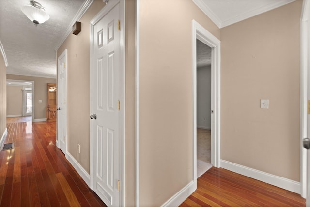 hallway featuring dark hardwood / wood-style floors, a textured ceiling, and ornamental molding