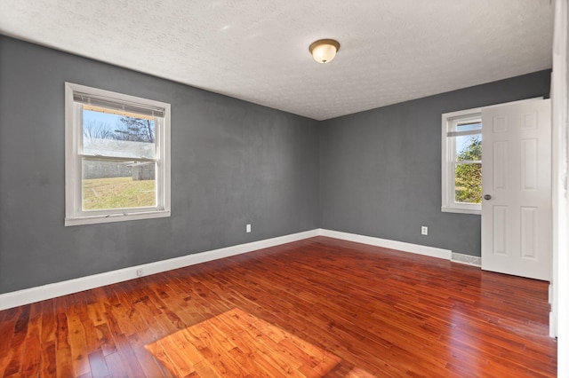 empty room with hardwood / wood-style floors and a textured ceiling