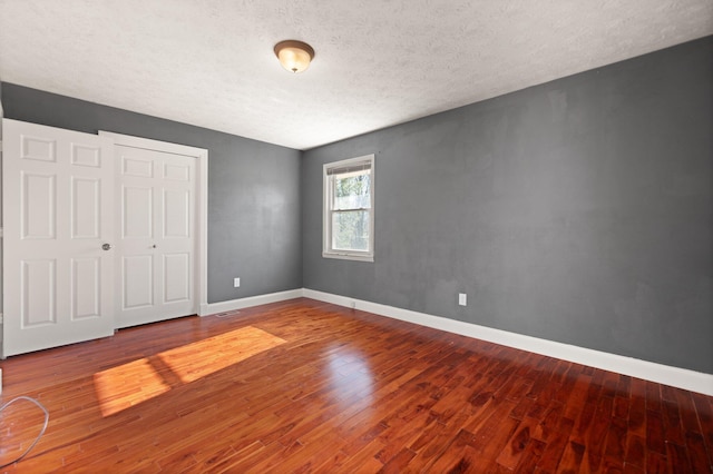 unfurnished bedroom with hardwood / wood-style floors, a textured ceiling, and a closet