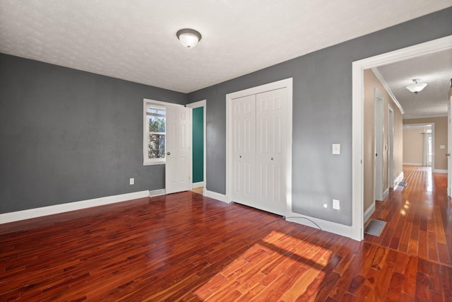 unfurnished bedroom featuring a textured ceiling, dark wood-type flooring, and a closet