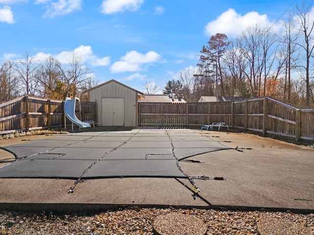 view of swimming pool featuring a storage shed, a patio, and a water slide