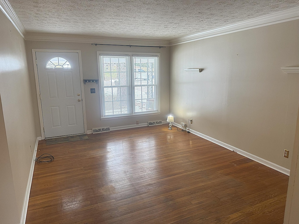 entrance foyer with baseboards, visible vents, ornamental molding, dark wood-style flooring, and a textured ceiling