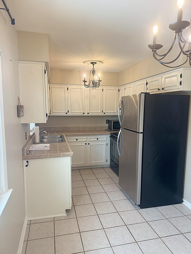 kitchen featuring a wealth of natural light, pendant lighting, white cabinets, stainless steel fridge, and a chandelier