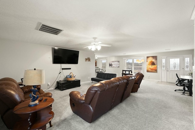 carpeted living room featuring ceiling fan and a textured ceiling