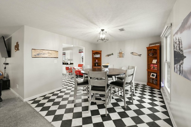 dining space with an inviting chandelier and a textured ceiling