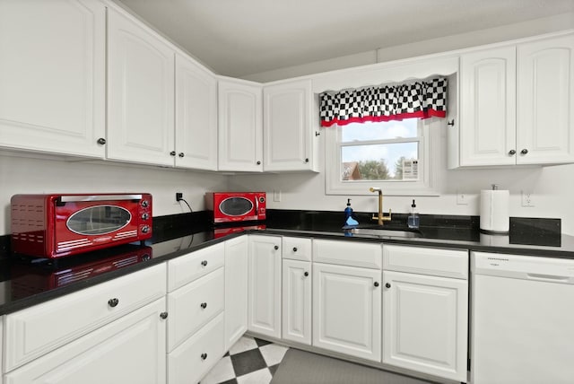 kitchen with white dishwasher, sink, and white cabinets