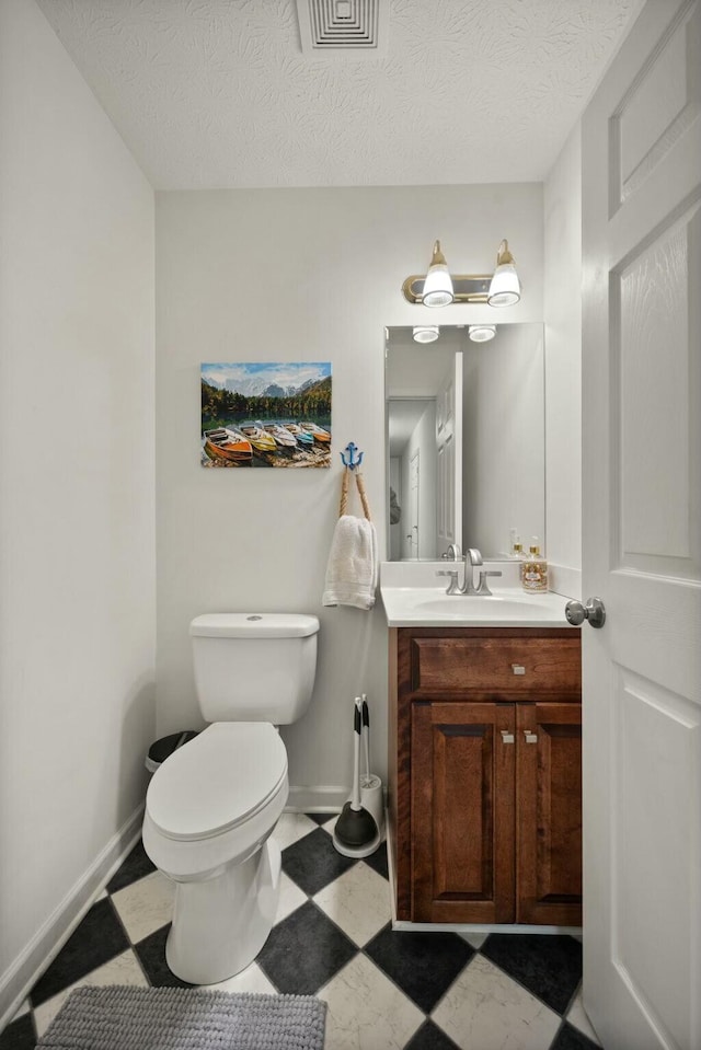 bathroom with vanity, toilet, and a textured ceiling