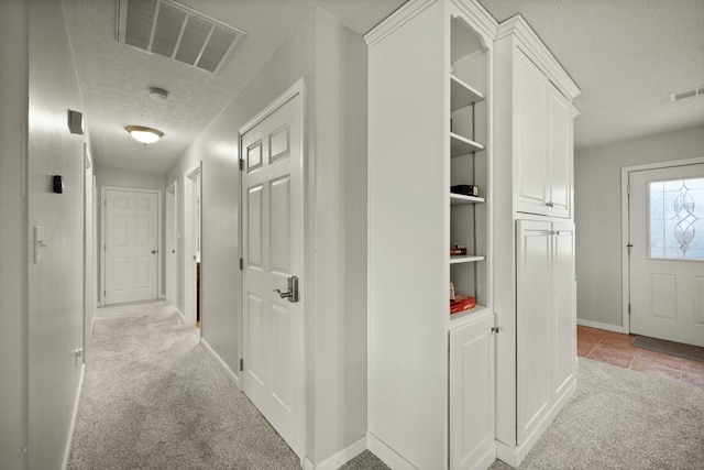 hall with light carpet and a textured ceiling