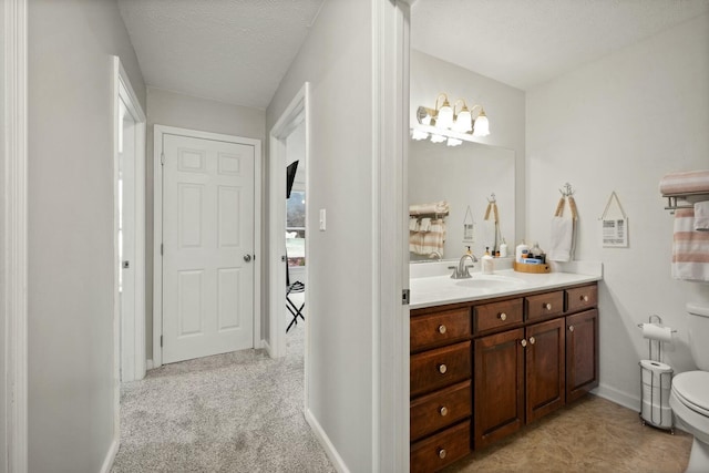 bathroom with vanity, toilet, and a textured ceiling