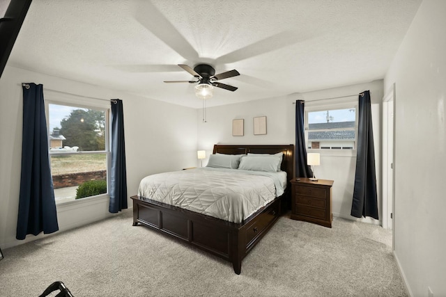 carpeted bedroom with ceiling fan and a textured ceiling