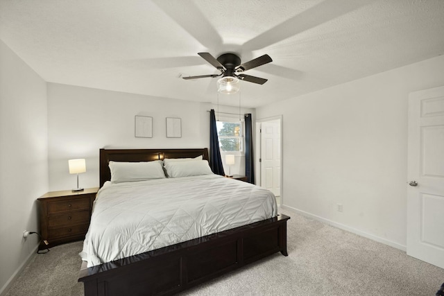 bedroom featuring ceiling fan, light colored carpet, and a textured ceiling