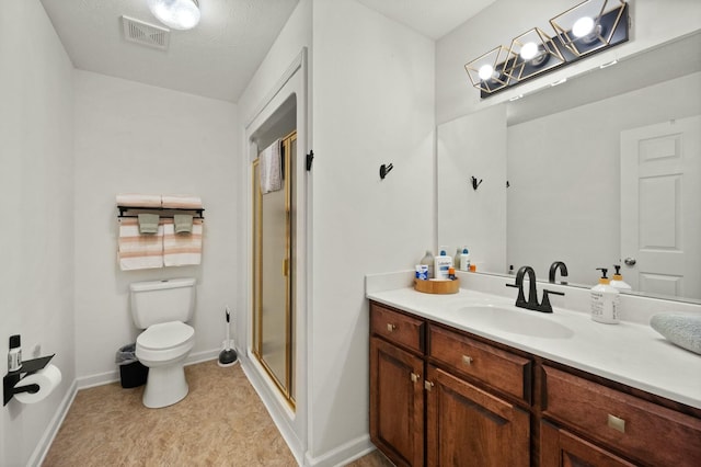 bathroom featuring vanity, a shower with door, and toilet