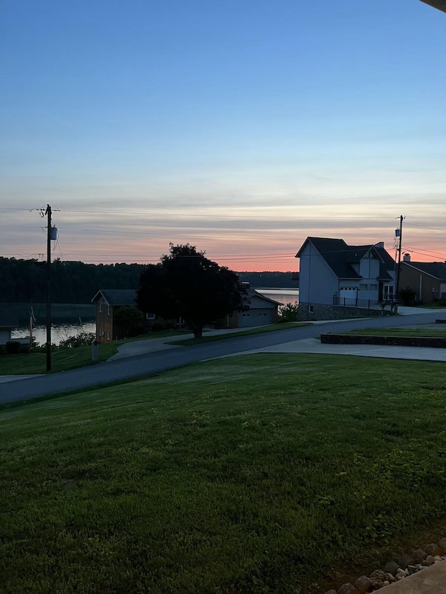 yard at dusk featuring a water view