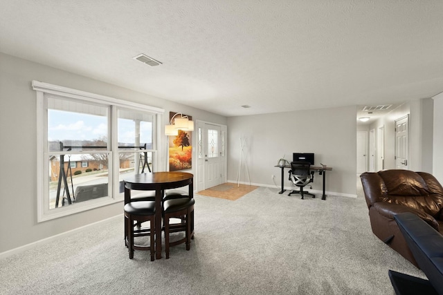 carpeted dining space with a textured ceiling