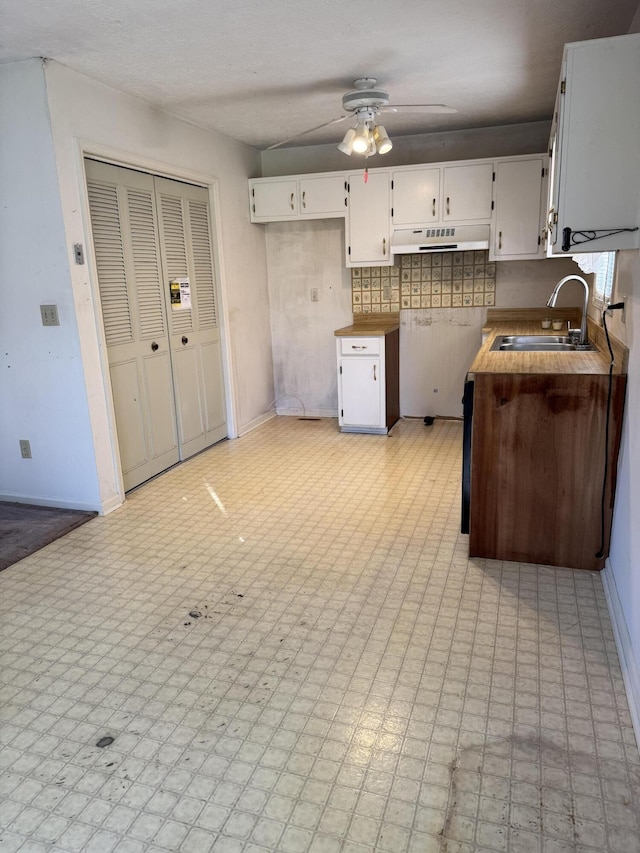 kitchen with decorative backsplash, white cabinetry, sink, and ceiling fan