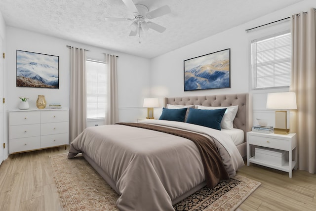 bedroom featuring ceiling fan, light hardwood / wood-style floors, a textured ceiling, and multiple windows