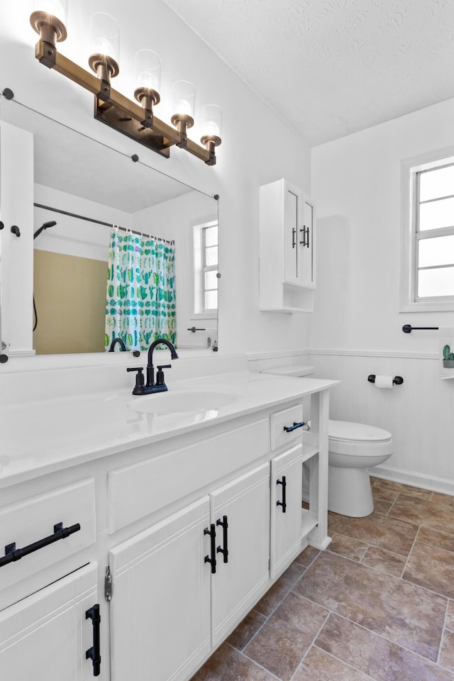 bathroom featuring a textured ceiling, vanity, toilet, and walk in shower