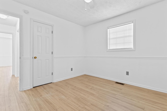 empty room featuring a textured ceiling, light hardwood / wood-style floors, and ceiling fan