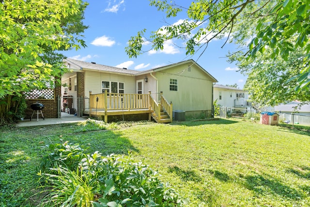 back of property with a yard, a patio, and a wooden deck