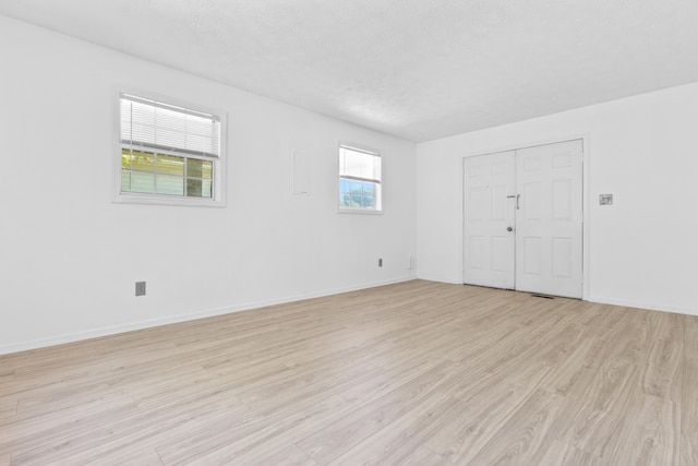 unfurnished room with light hardwood / wood-style flooring and a textured ceiling