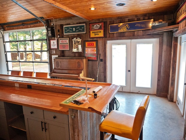 bar with french doors, wood ceiling, wood counters, and wood walls