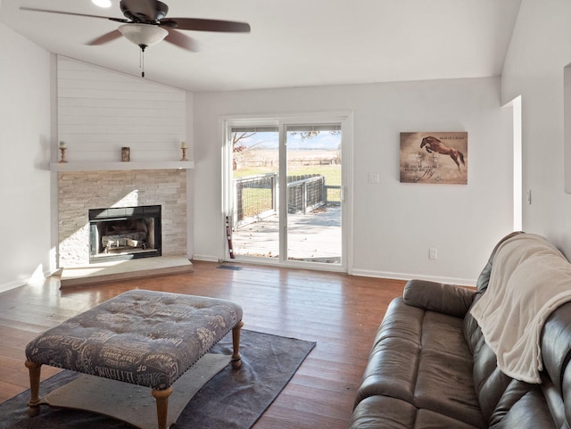 living room with ceiling fan, wood-type flooring, lofted ceiling, and a fireplace