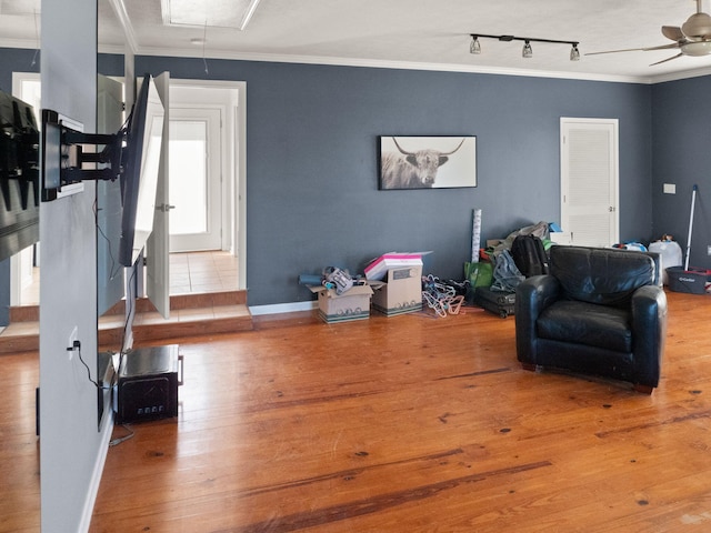 living room featuring track lighting, ornamental molding, and light hardwood / wood-style floors