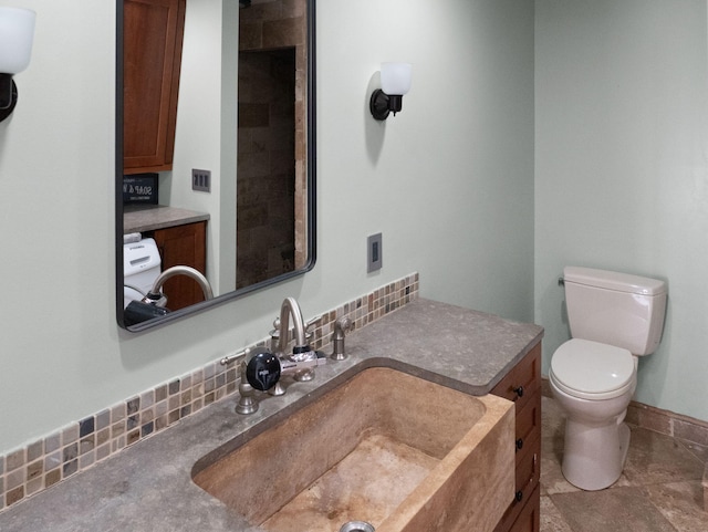 bathroom featuring toilet, backsplash, and sink