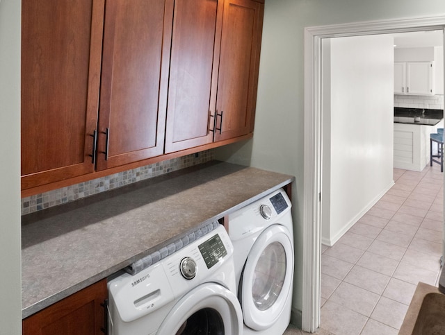 clothes washing area featuring cabinets, separate washer and dryer, and light tile patterned floors