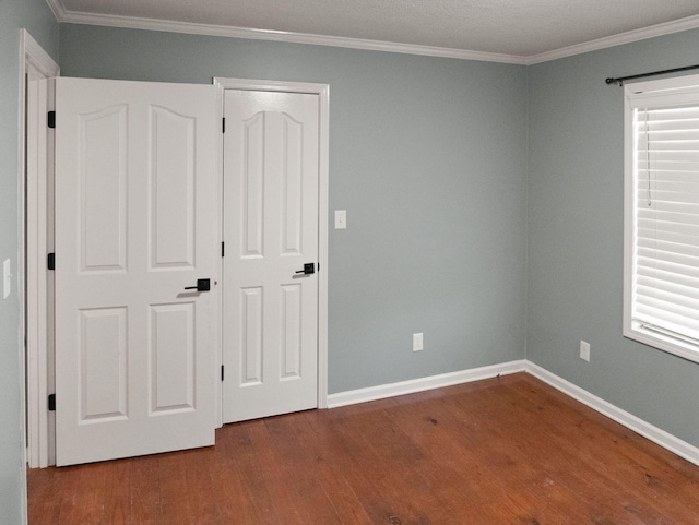 unfurnished bedroom featuring a closet, ornamental molding, hardwood / wood-style floors, and multiple windows