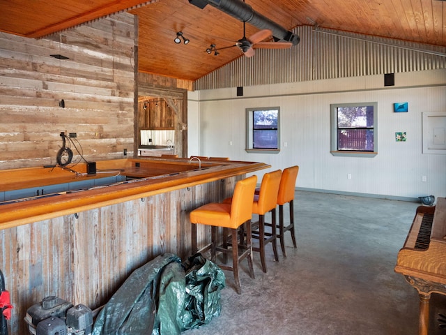 bar featuring vaulted ceiling, ceiling fan, wood ceiling, and wood walls