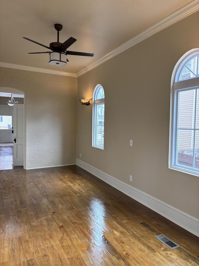 empty room with wood-type flooring, ceiling fan, and crown molding