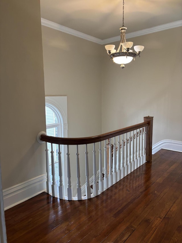 stairway featuring hardwood / wood-style floors, a notable chandelier, and ornamental molding